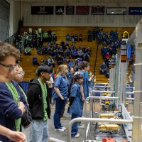 A line of students watch their robots on the field